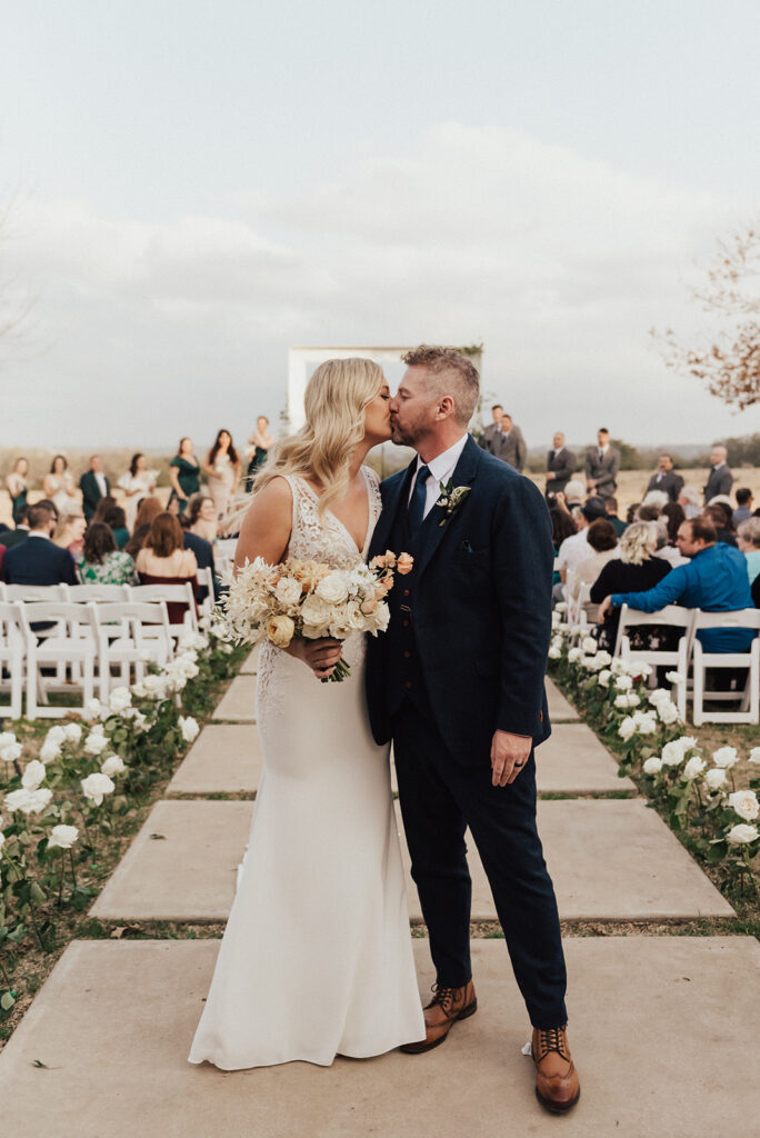 bride and groom share kiss during wedding recessional