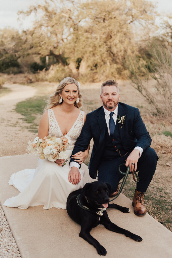 bride in deep v-neck wedding dress with groom in dark navy suit with their dog