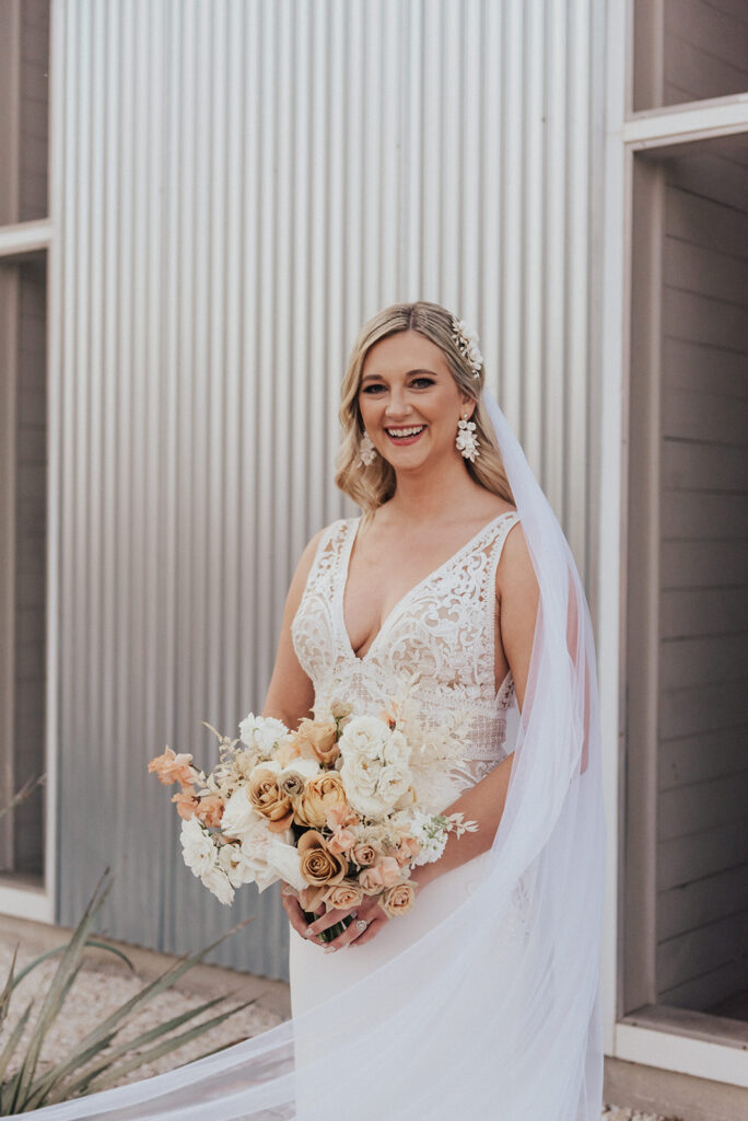bride in deep v-neck wedding dress with white floral bouquet and veil