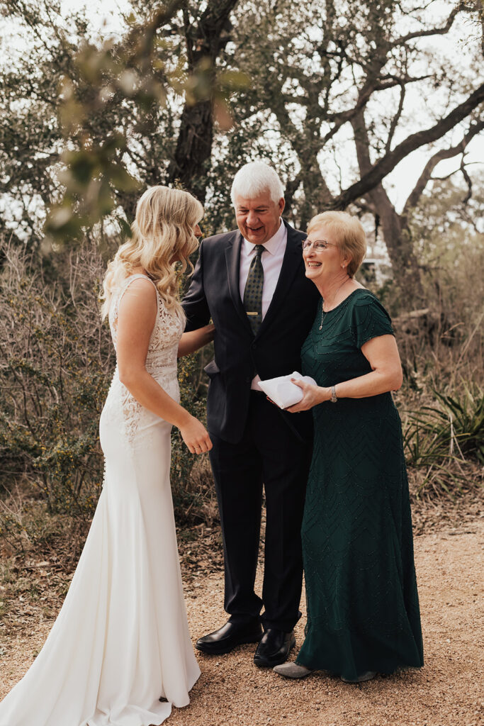 bride in deep v-neck wedding dress with lace details does first look with father and mother 