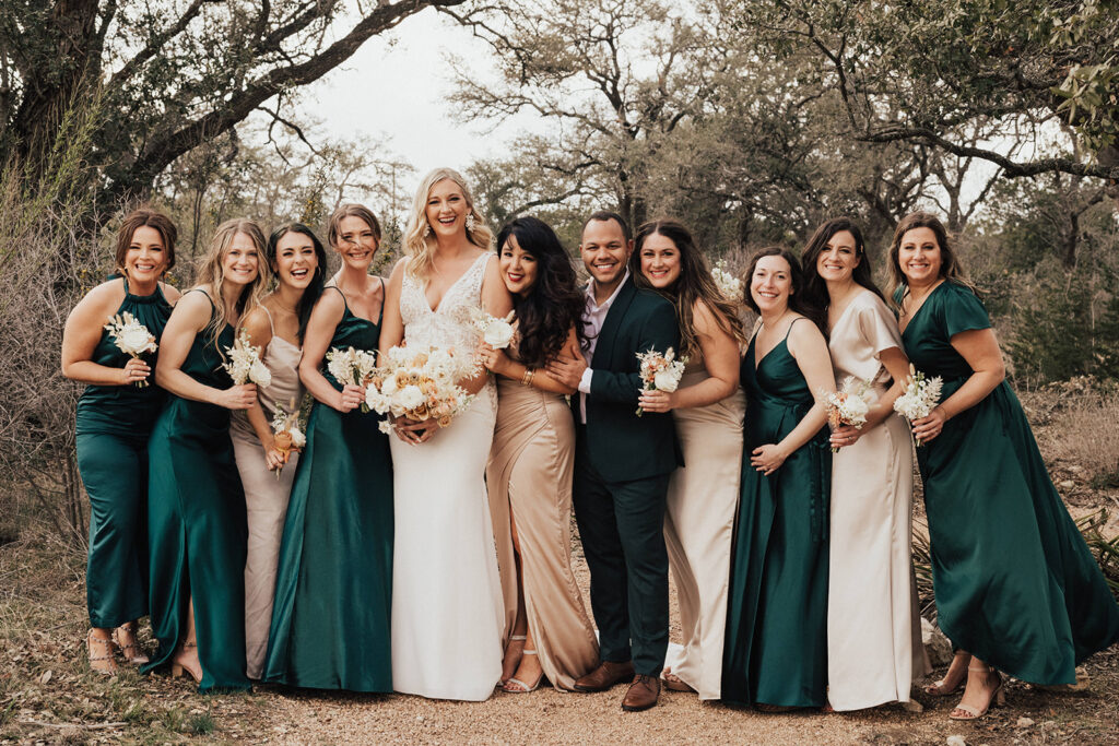 bride in deep v-neck wedding dress with co-ed wedding party in dark green and champagne colored outfits