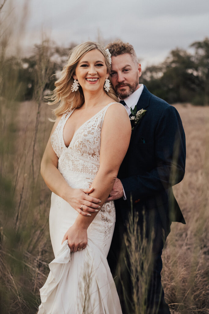 sunset photos of bride in deep v-neck wedding dress with groom in navy blue suit and brown shoes