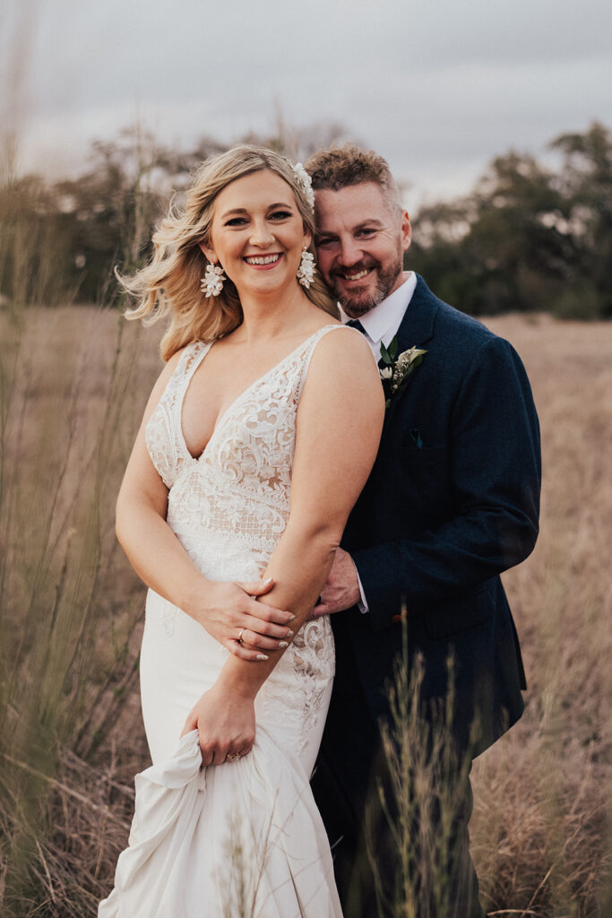 sunset photos of bride in deep v-neck wedding dress with groom in navy blue suit and brown shoes