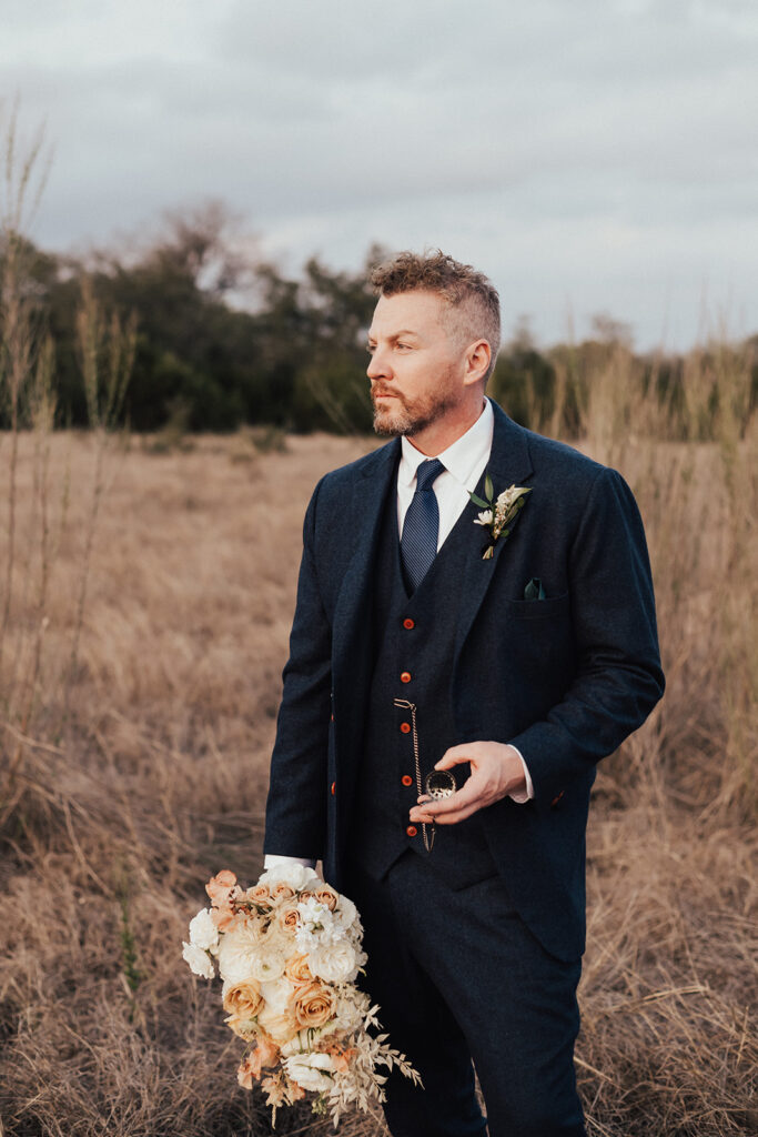 groom in navy blue suit and brown shoes holding pocket watch