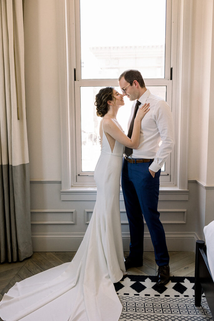 bride in contemporary minimalist wedding dress getting ready with groom in navy suit and black tie