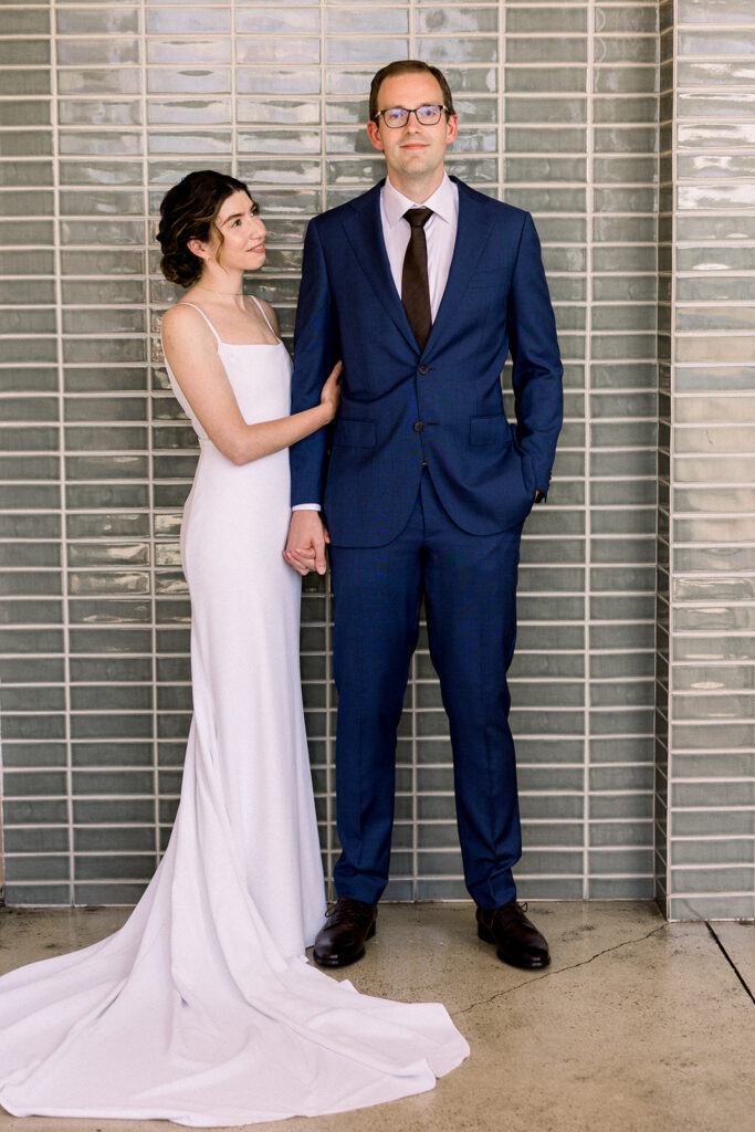 wedding portrait of bride in contemporary minimalist wedding dress and groom in navy suit and black tie