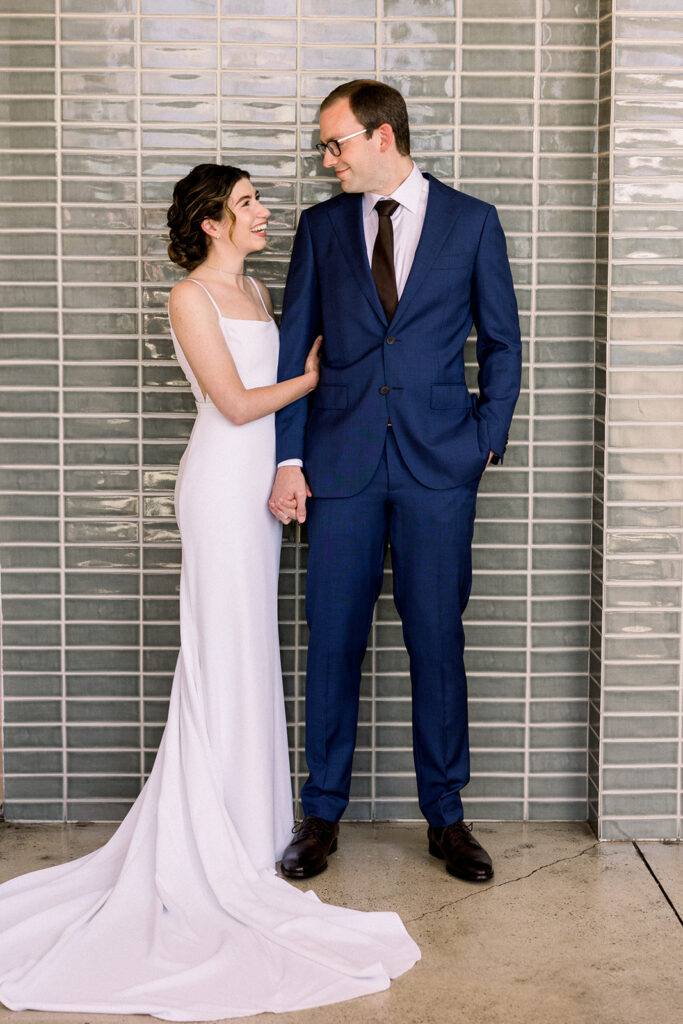 wedding portrait of bride in contemporary minimalist wedding dress and groom in navy suit and black tie