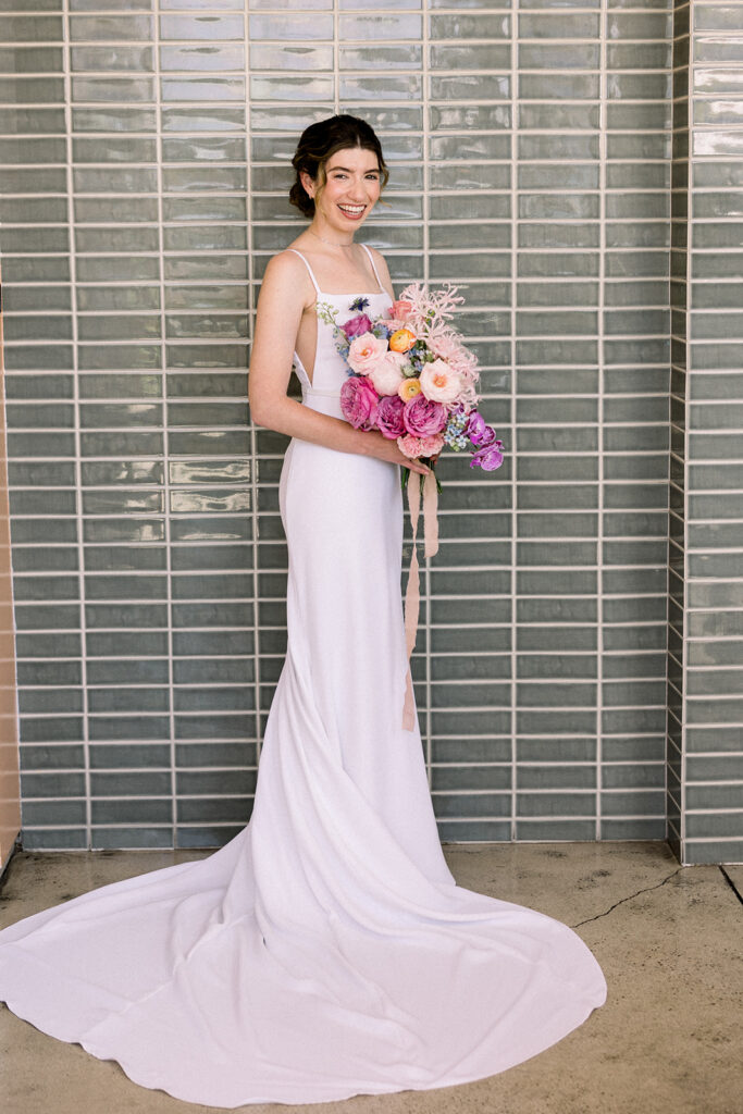 wedding portrait of bride in contemporary minimalist wedding dress holing colorful pastel bouquet 