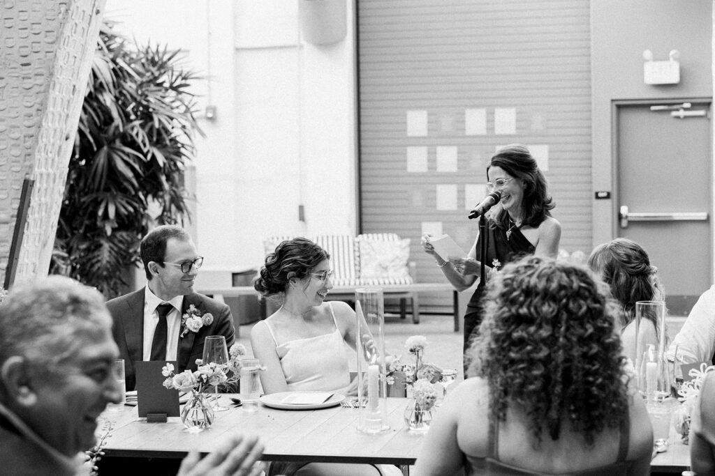 black and white photo of bride and groom during speeches at reception 