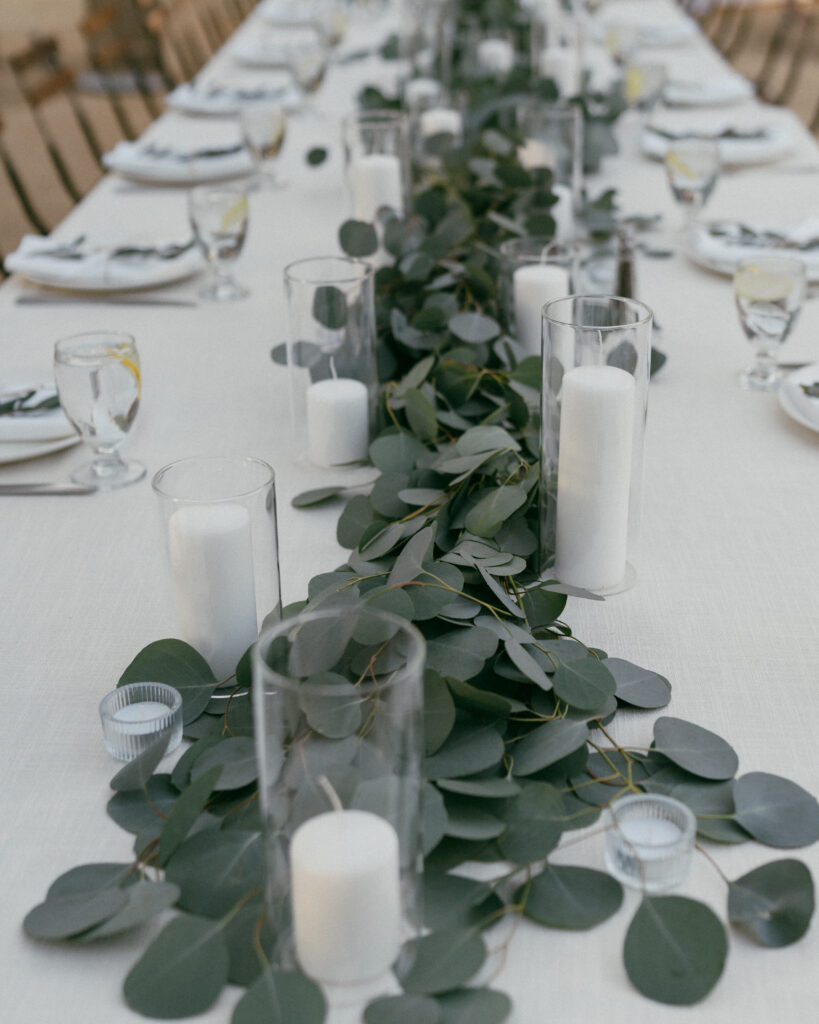 large elegant understated outdoor wedding reception with long tables in white linen, eucalyptus leaves and wooden patio chairs
