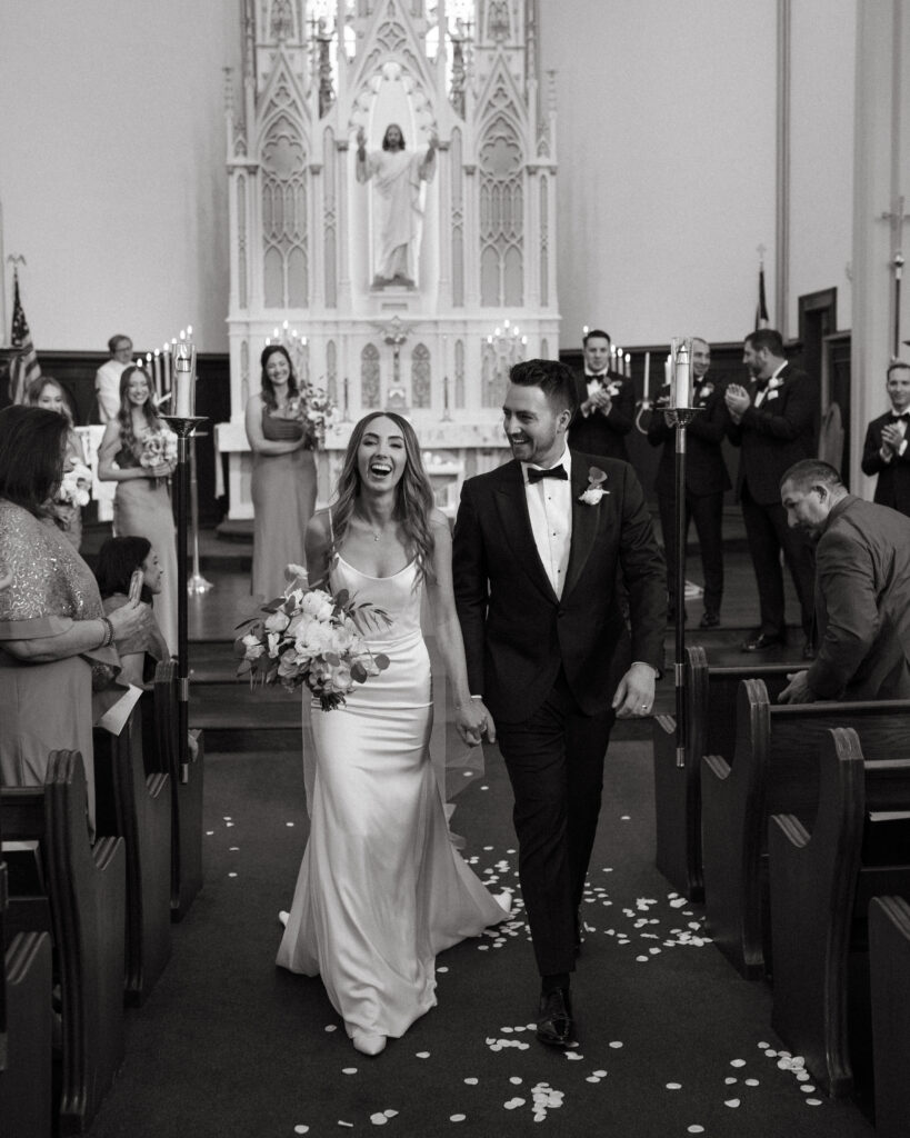 church wedding ceremony recessional with bride in modern minimalist wedding dress and groom in classic black tuxedo suit