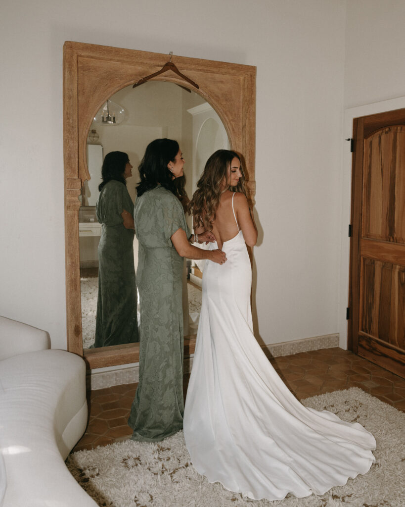 bride with mom getting into wedding dress