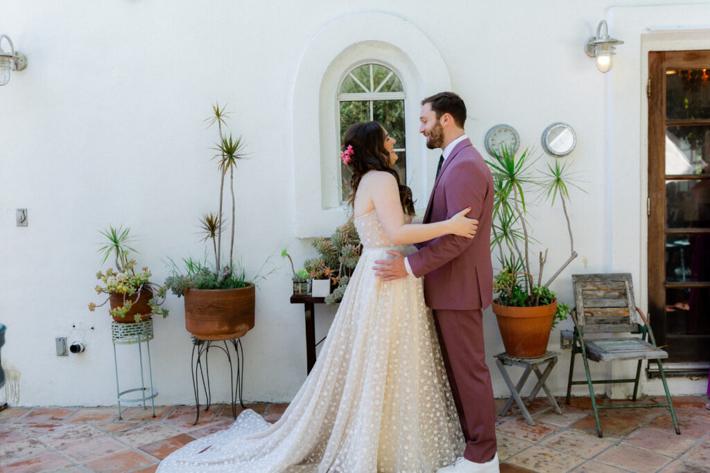 first look with bride in strapless wedding dress and groom in merlot suit