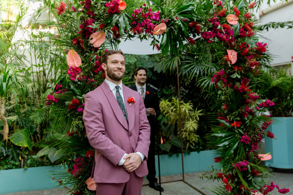groom in merlot suit during wedding ceremony