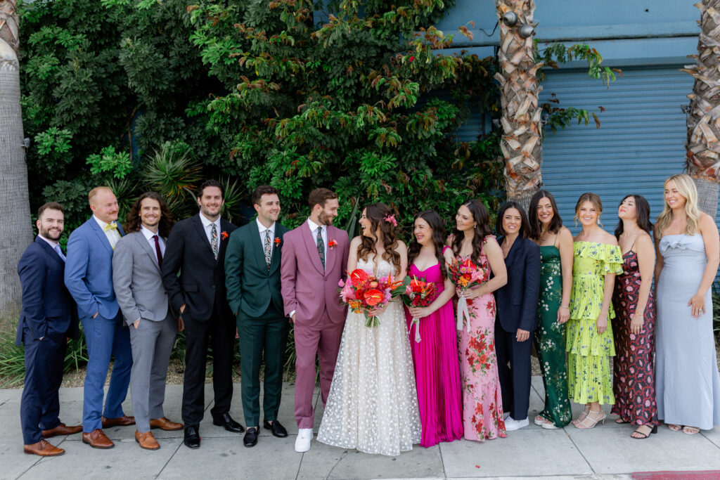 bride in strapless wedding dress and groom in merlot suit in front of Valentine DTLA with wedding party in mixed outfits