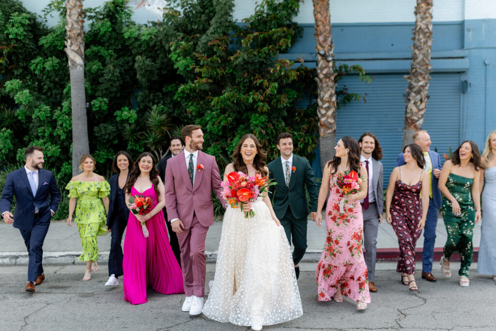 bride in strapless wedding dress and groom in merlot suit in front of Valentine DTLA with wedding party in mixed outfits