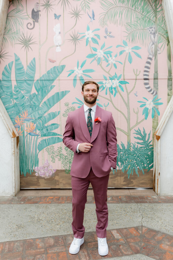 groom in merlot colored suit with white shoes and floral tie