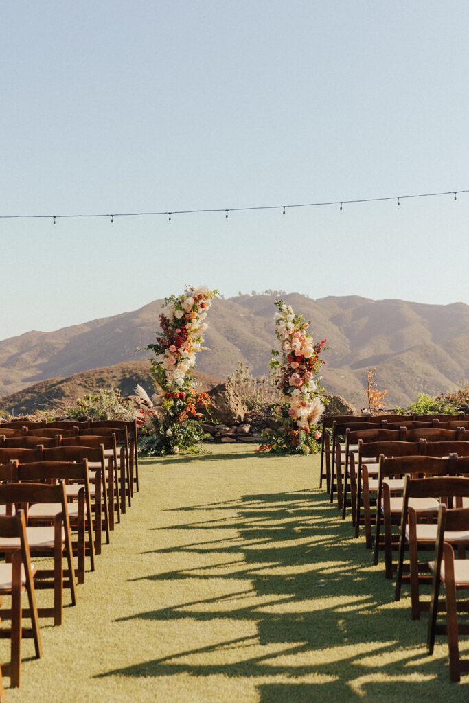 citrus inspired fall wedding ceremony with asymmetrical wedding arch and wooden chairs