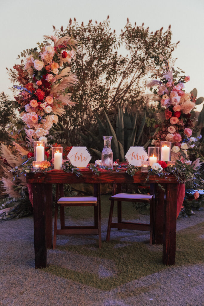 fall wedding reception tables with wooden farmhouse tables and burnt orange chargers, napkins and citrus slice garnish 