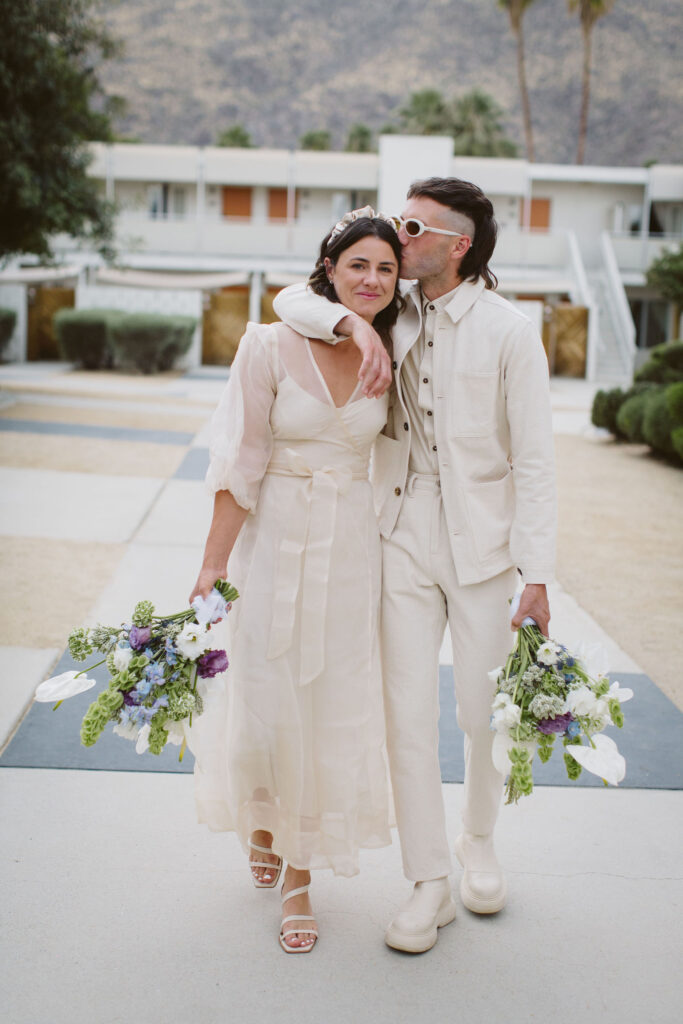 portraits of bride in modern wedding dress with sheer overlay and satin headband and groom in all white outfit with both holding bouquets