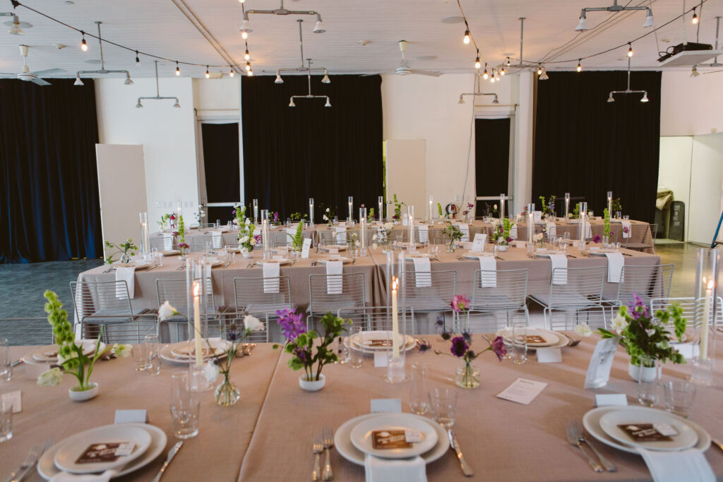 modern minimalist wedding reception with neutral linens, structured white chairs and purple, green and white floral arrangements