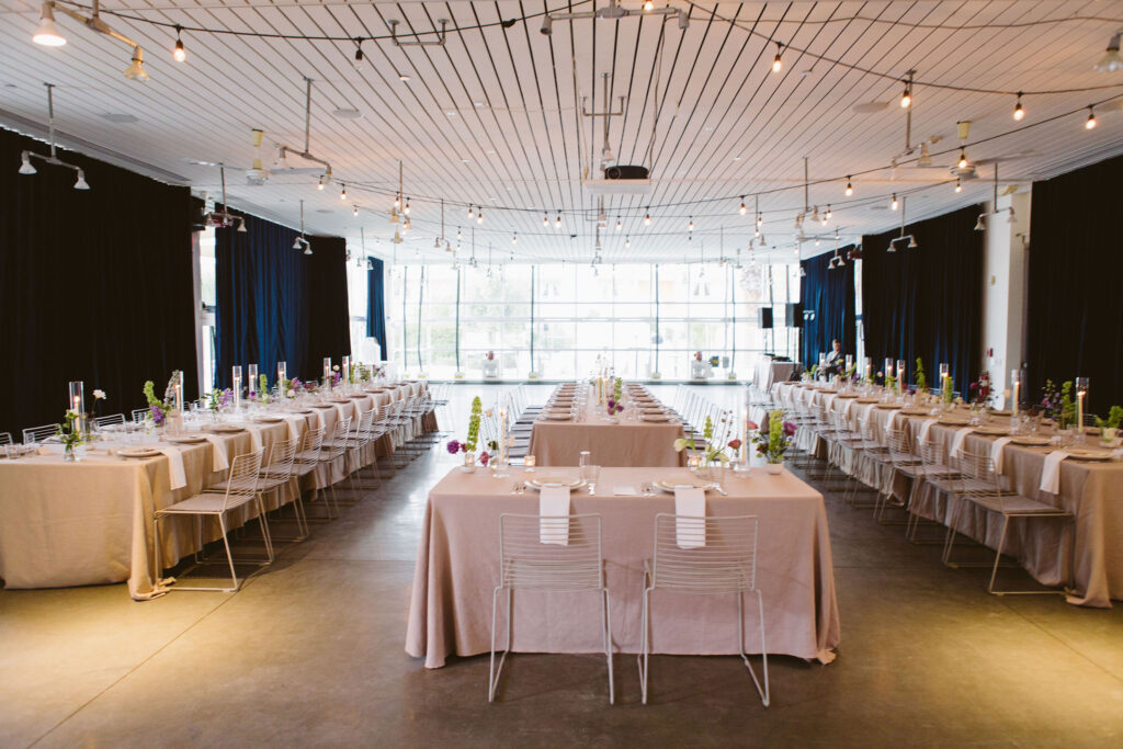 modern minimalist wedding reception with neutral linens, structured white chairs and purple, green and white floral arrangements