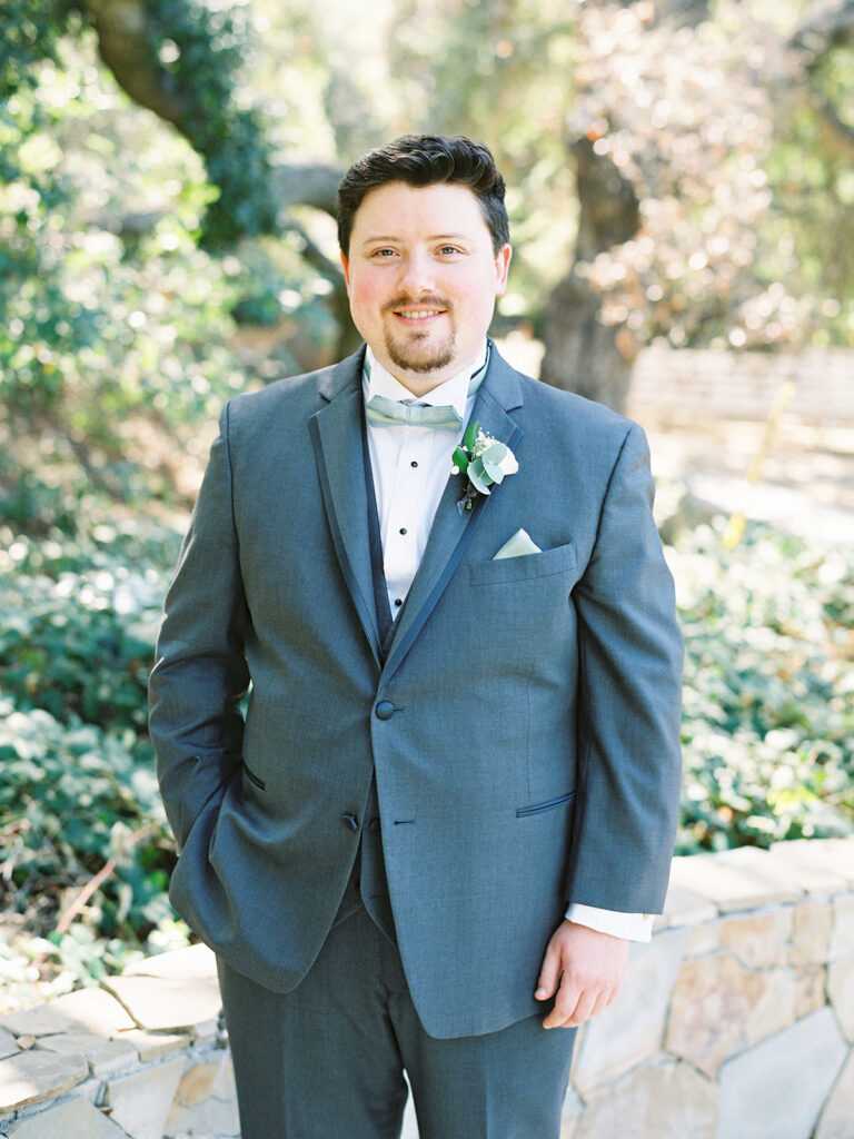 groom in grey blue suit with teal bow tie