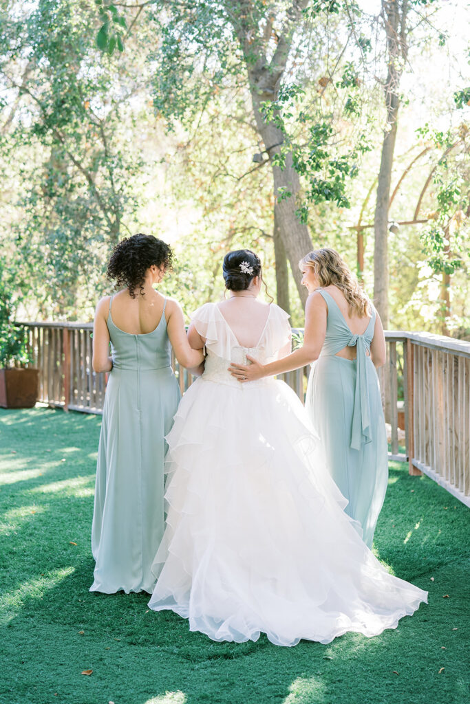 bride in organza ballroom wedding dress with bridesmaids in soft teal dresses