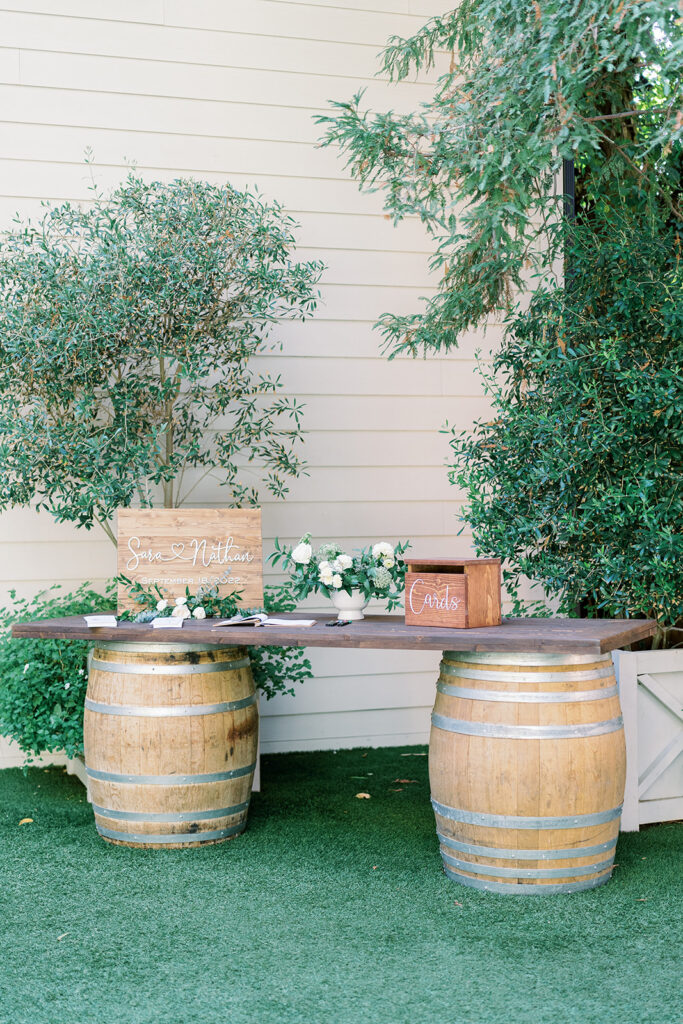 light and airy wedding welcome table with wine barrel and wooden card box