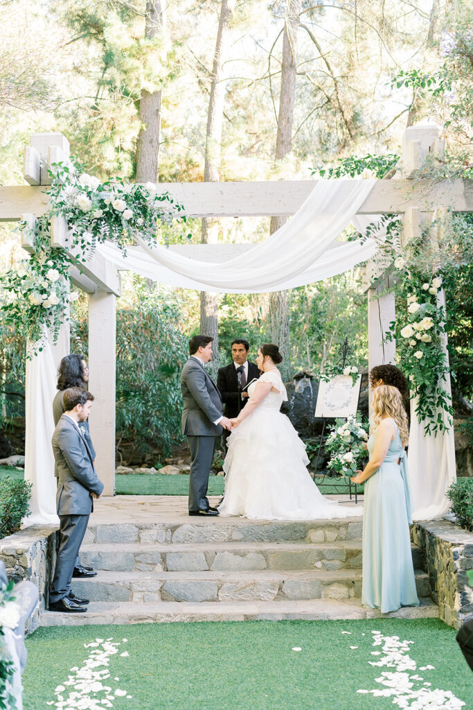 light and airy wedding ceremony at Calamigos Redwood Room with white drapery and flowers