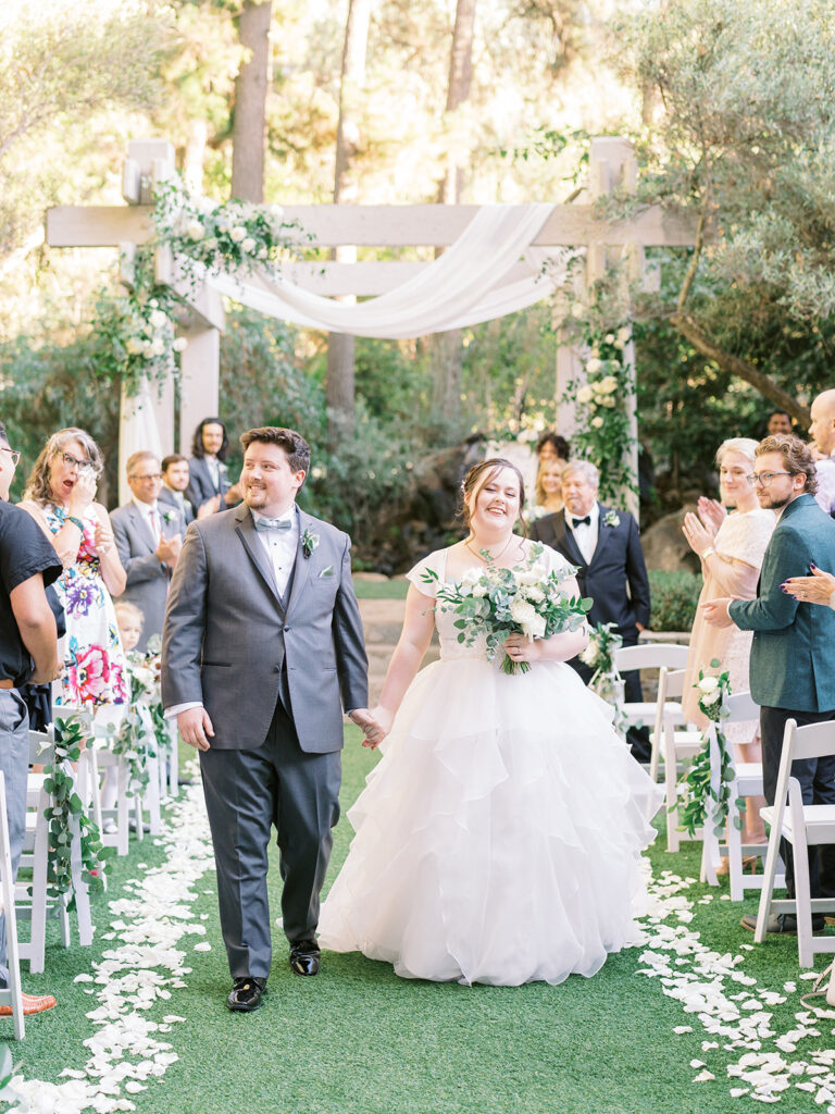 bride and groom recessional during light and airy wedding ceremony at Calamigos Redwood Room with white drapery and flowers