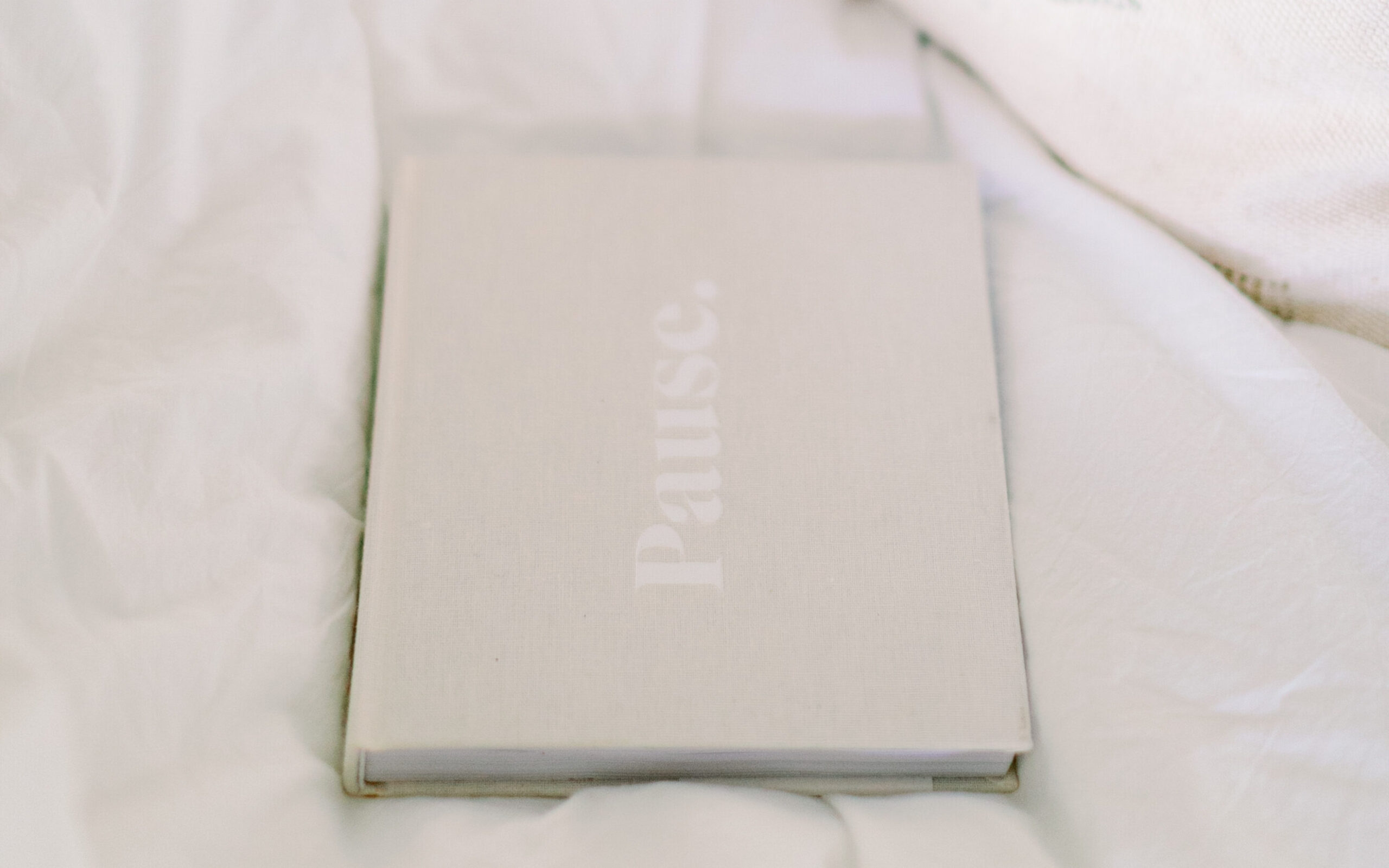 A notebook titled Pause sits on bed as a reminder of new year goals