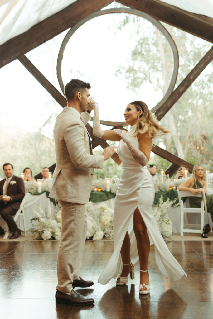 bride in satin halter style wedding dress with gloves and groom in khaki plaid suit first dance at wedding reception at Calamigos Ranch