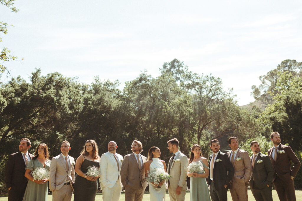 bride and groom stand with co-ed wedding party in mixed wedding outfits