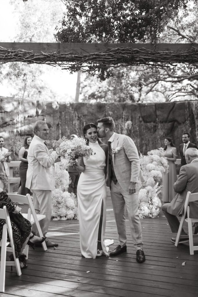 bride and groom kiss during wedding recessional 