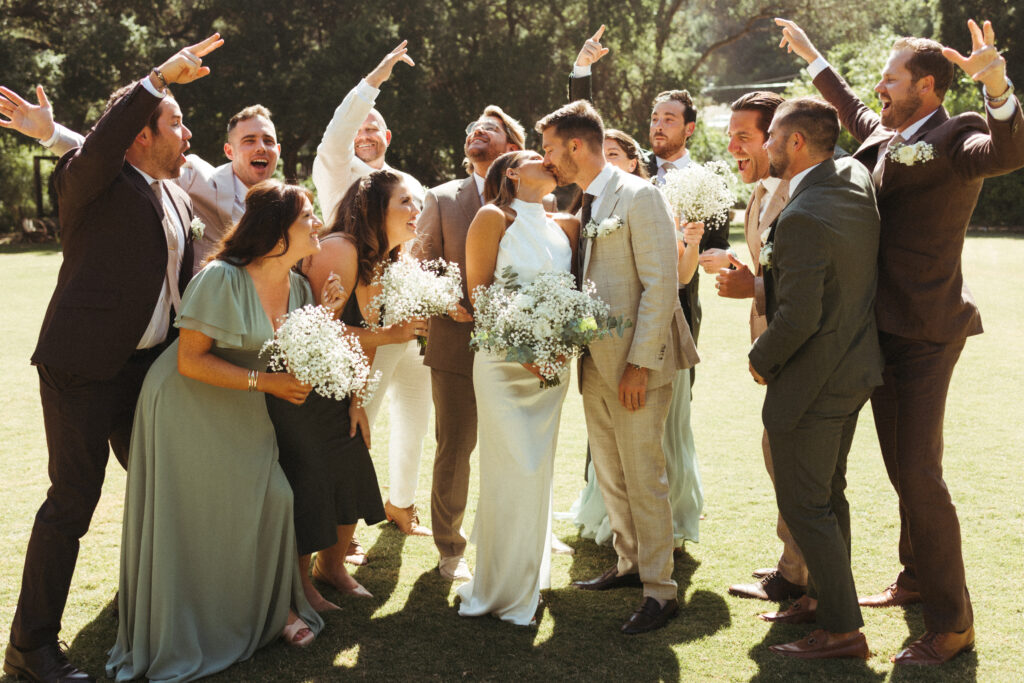 bride and groom stand with co-ed wedding party in mixed wedding outfits