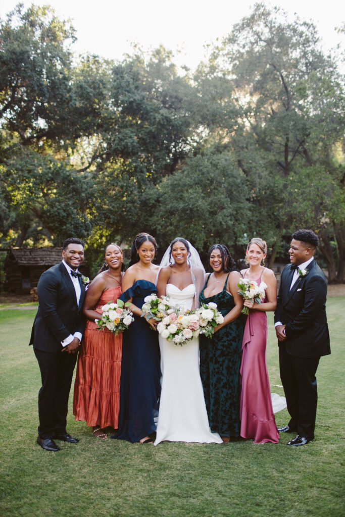 bride in modern minimalist wedding dress stands with co-ed wedding party in mix wedding attire at Calamigos Ranch