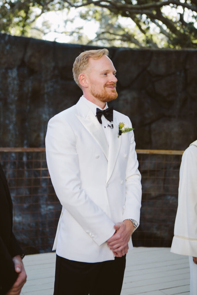 stylish groom in white tuxedo jacket with black bowtie 