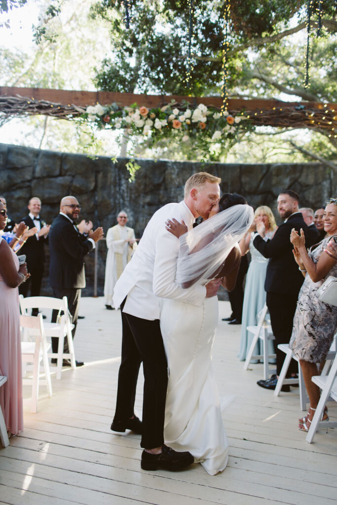 bride and groom kiss at the end of the aisle during wedding ceremony at Calamigos Ranch