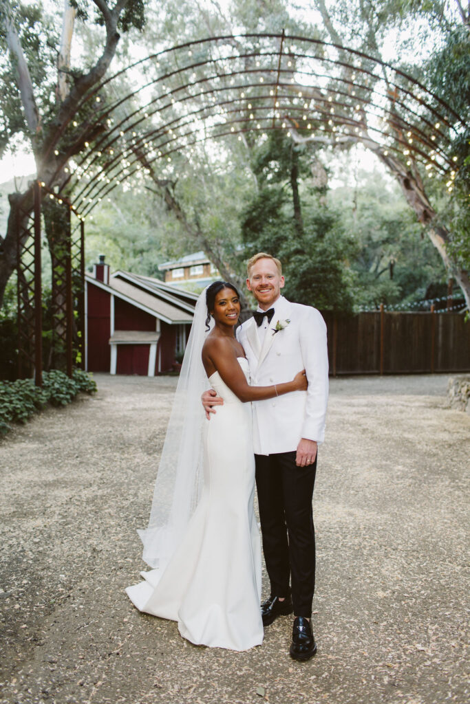 Stylish bride in modern minimalist wedding dress and cathedral veil with groom in white tuxedo jacket at Calamigos Ranch 
