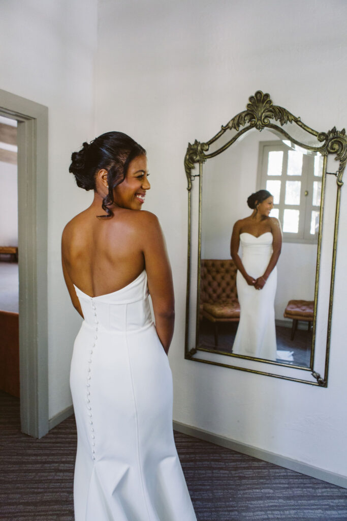 stylish bride in minimalist modern wedding dress with buttons down the back getting ready for wedding day